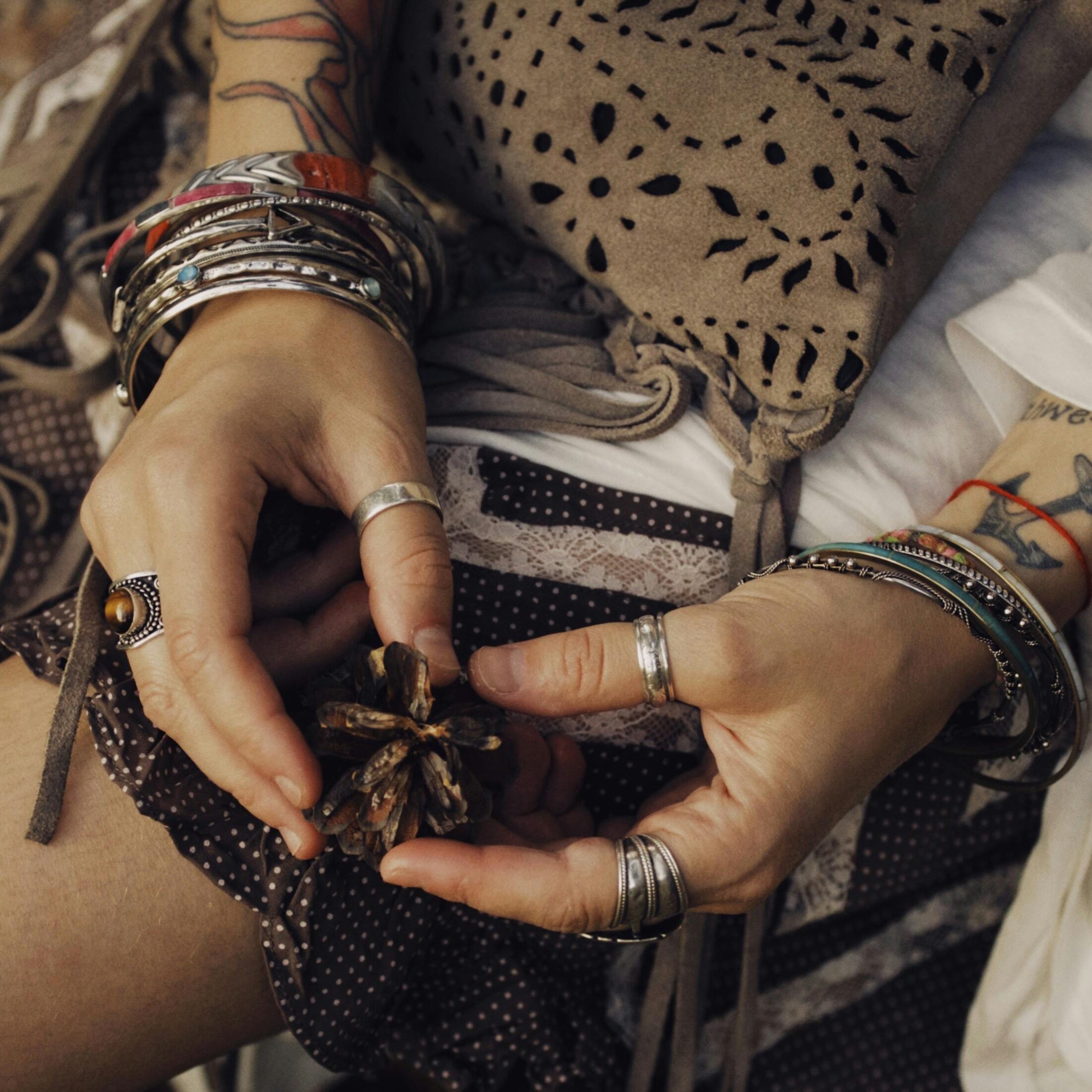 Hands wearing silver jewelry and bracelets, stacked naturally